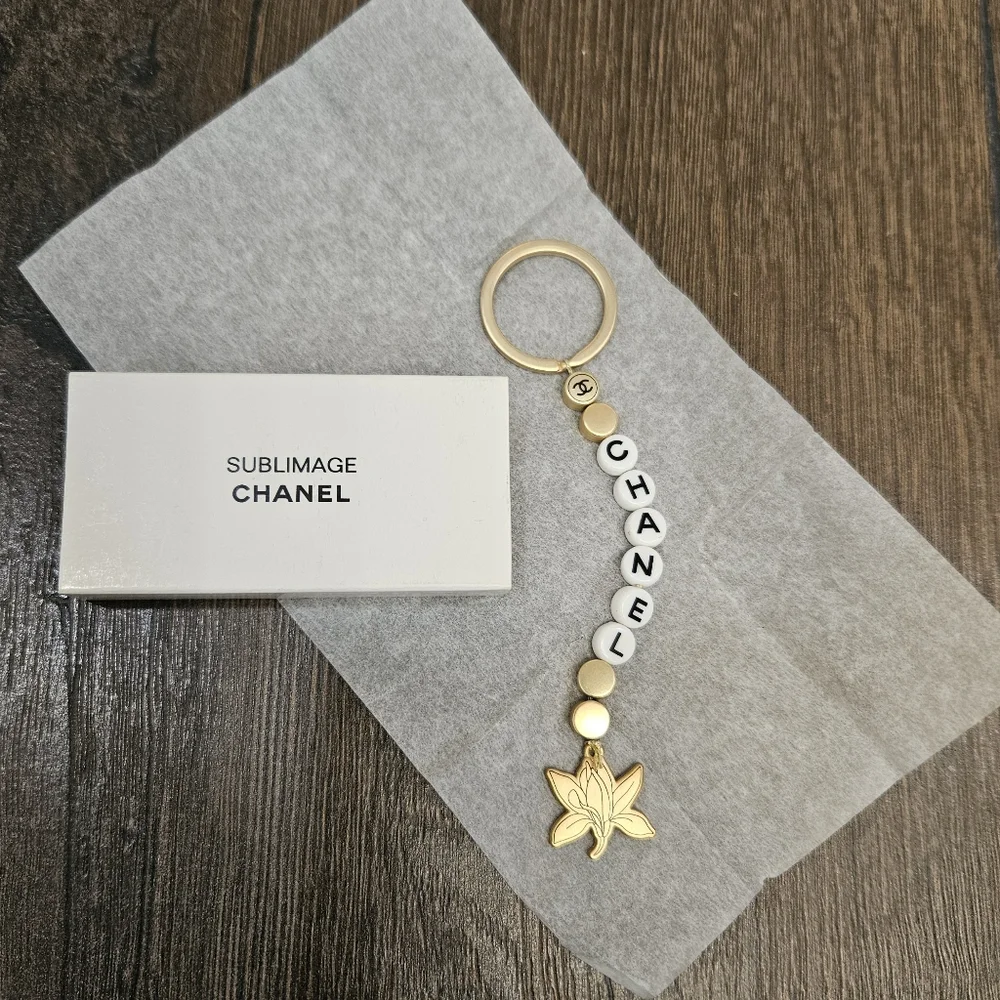 NIB CHANEL Sublimage Gold & White Beaded Keychain with Flower Charm